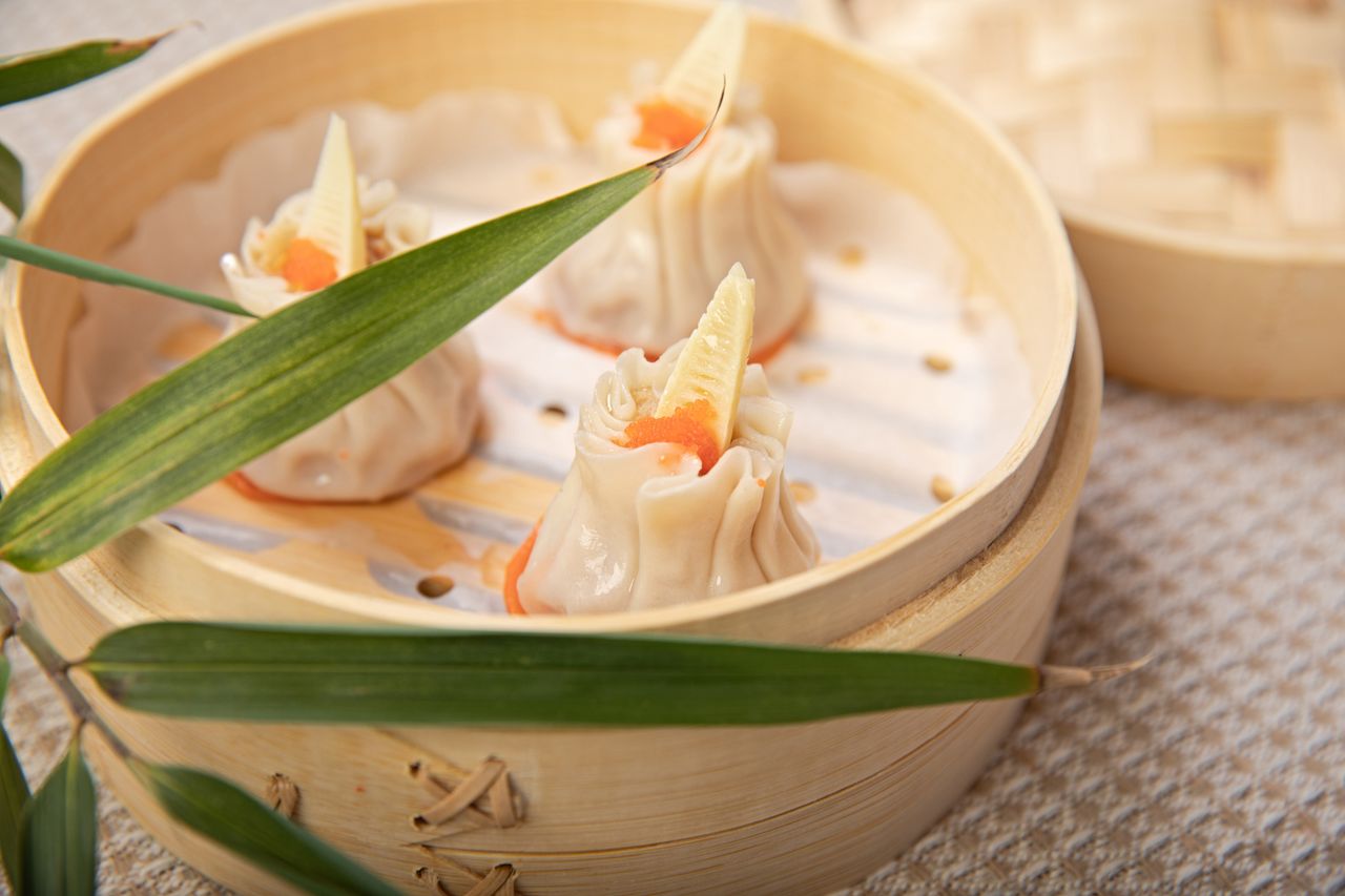 Home Close-up of gourmet shrimp dumplings in a steamer with bamboo leaves.