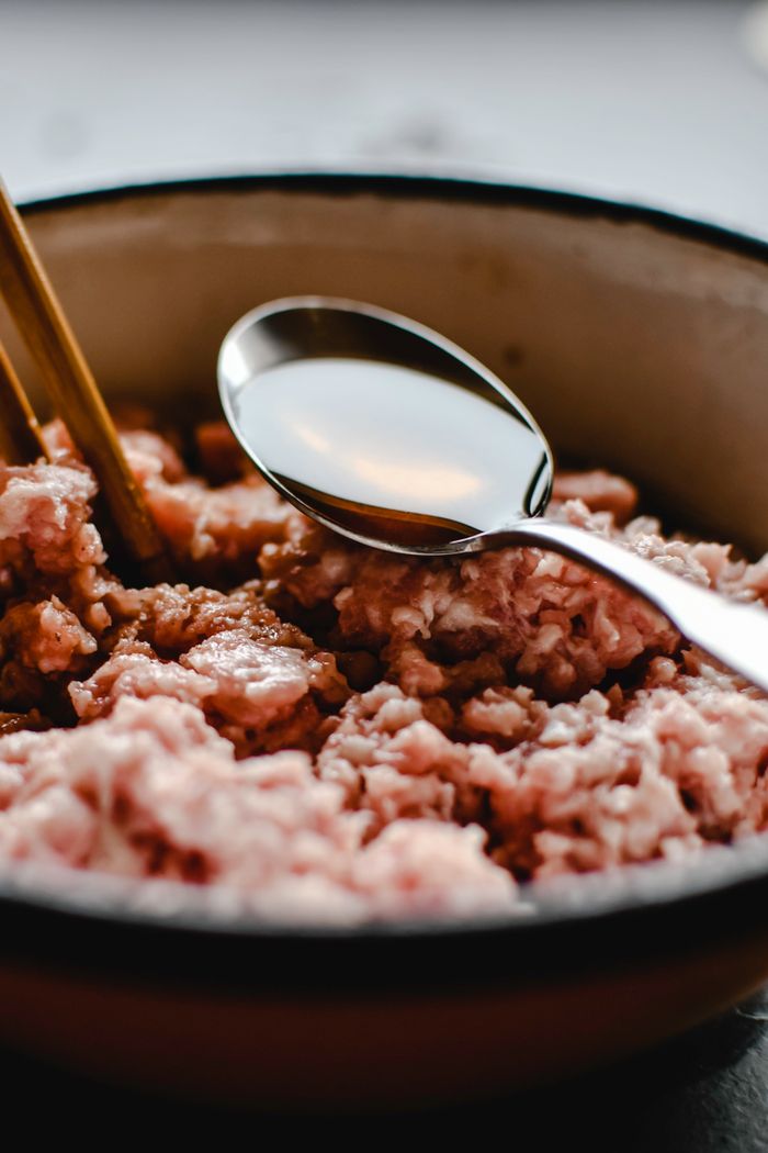 Home Delicious uncooked minced pork in a bowl with chopsticks and spoon, perfect for food prep.